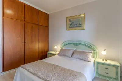 a bedroom with a white bed and wooden cabinets at Alegria Apart. with Pool, by Pausa Holiday Rentals in Estreito da Calheta