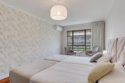 a white bedroom with a large bed and a window at Stay In Arriaga Avenue 09, by Pausa H. Rentals in Funchal
