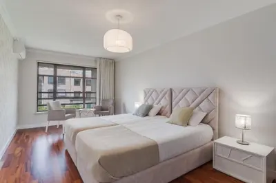 a white bedroom with a large bed and a window at Stay In Arriaga Avenue 09, by Pausa H. Rentals in Funchal