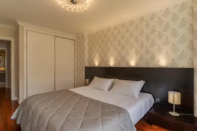 a bedroom with a large bed and a chandelier at Stay In Avenue Arriaga 10, by Pausa H. Rentals in Funchal