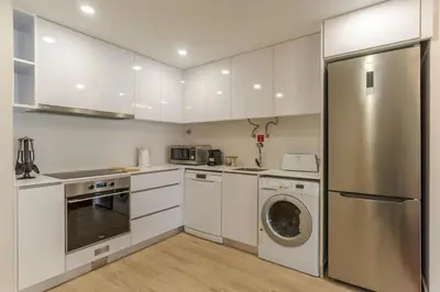 a kitchen with white cabinets and a stainless steel refrigerator at Stay In Avenue Arriaga 10, by Pausa H. Rentals in Funchal