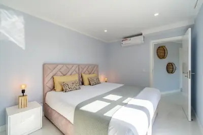 a white bedroom with a large bed with yellow pillows at Stay In St. Catarina Park, by PAUSA H. Rentals in Funchal