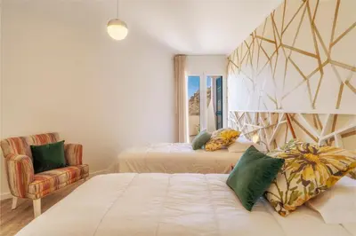 a bedroom with two beds and a chair at Renala I-Apart. 