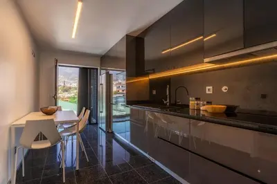 a kitchen with black cabinets and a table and chairs at Renala II - Apart, With Pool, by Pausa H. Rentals in Funchal