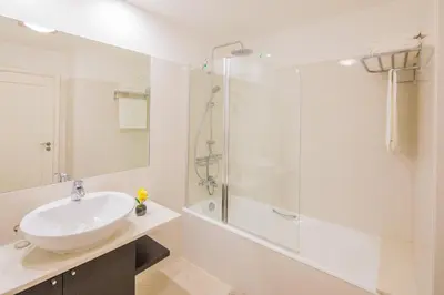 a white bathroom with a sink and a shower at Rodamar Penthouse in Funchal