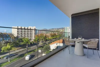 a balcony with a table and chairs and a view of a city at Stay In S.Lucas Residence, by Pausa H. Rentals in Funchal