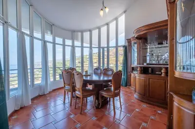 a dining room with a table and chairs and windows at Casa Almada in Ribeira Brava