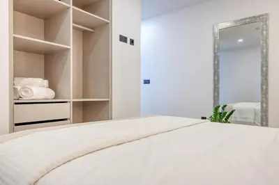 a white bedroom with a bed and a mirror at BSE15 Apartments 2D, a Home in Madeira in Funchal