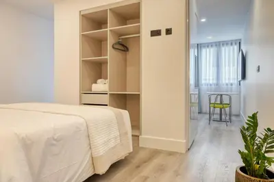 a white bedroom with a bed and a chair at BSE15 Apartments 2D, a Home in Madeira in Funchal