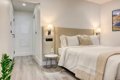 a white bedroom with two beds and a table at BSE15 Apartments 2D, a Home in Madeira in Funchal