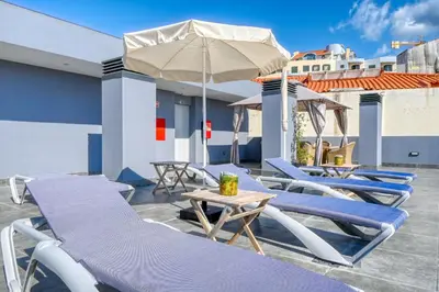 a patio with blue lounge chairs and an umbrella at BSE15 Apartments 2D, a Home in Madeira in Funchal