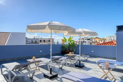 a patio with chairs and tables and umbrellas on a roof at BSE15 Apartments 2E, a Home in Madeira in Funchal