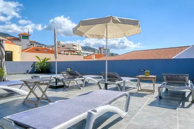 a patio with tables and chairs and an umbrella at BSE15 Apartments 2E, a Home in Madeira in Funchal