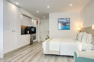 a white bedroom with a large bed and a flat screen tv at BSE15 Apartments 3H, a Home in Madeira in Funchal
