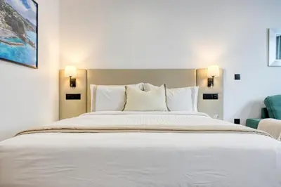 a bedroom with a large white bed and a blue chair at BSE15 Apartments 3H, a Home in Madeira in Funchal