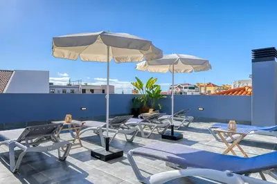 a patio with chairs and umbrellas on a roof at BSE15 Apartments 4L, a Home in Madeira in Funchal