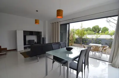 a dining room and living room with a table and chairs at Vilas Espírito Santo in Porto Santo