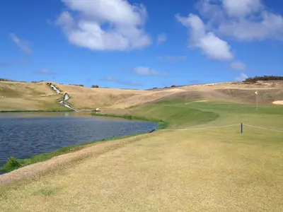 a golf course with a lake next to a hill at Vilas Espírito Santo in Porto Santo