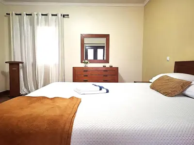 a bedroom with a bed with a mirror and a dresser at Quartos em Vila Paradise Porto da Cruz in Porto da Cruz