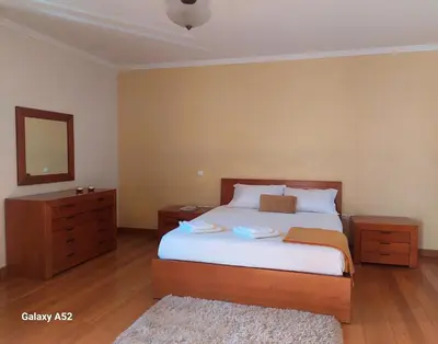 a bedroom with a bed and a dresser and a mirror at Quartos em Vila Paradise Porto da Cruz in Porto da Cruz
