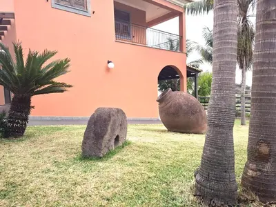 a building with a large rock next to a palm tree at Quartos em Vila Paradise Porto da Cruz in Porto da Cruz