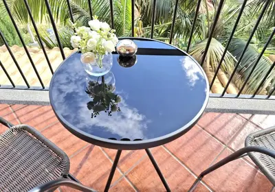 a glass table with a vase of flowers on it at Quartos em Vila Paradise Porto da Cruz in Porto da Cruz