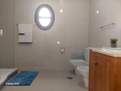a bathroom with a toilet and a sink and a window at Quartos em Vila Paradise Porto da Cruz in Porto da Cruz
