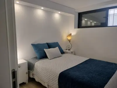 a bedroom with a bed with blue pillows and a window at MerakiHouse in Funchal