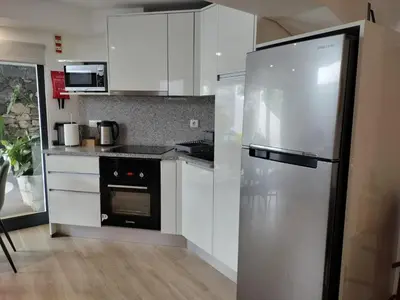 a kitchen with white cabinets and a stainless steel refrigerator at MerakiHouse in Funchal