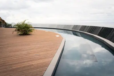 a swimming pool on a wooden deck next to the ocean at Varandas do Atlântico in Câmara de Lobos
