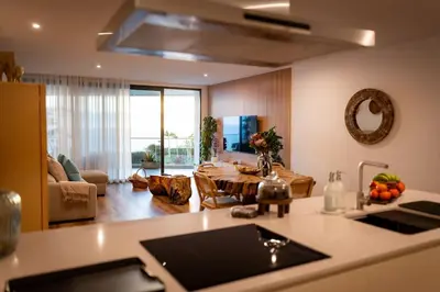 a kitchen with a table and a living room at Varandas do Atlântico in Câmara de Lobos
