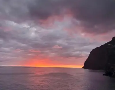 a sunset over a body of water with a mountain at Varandas do Atlântico in Câmara de Lobos