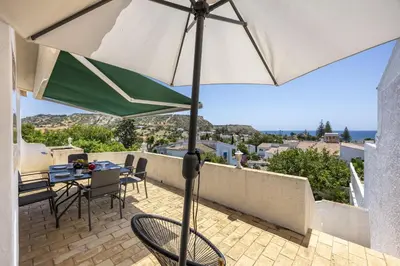 a patio with a table and an umbrella at CoolHousesAlgarve Luz, 3 bed linked house, pool, superb panoramic sea view, Casa das Buganvílias in Luz