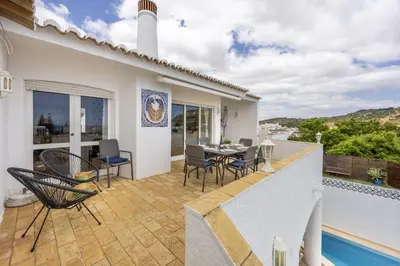 a villa with a swimming pool and a patio at CoolHousesAlgarve Luz, 3 bed linked house, pool, superb panoramic sea view, Casa das Buganvílias in Luz