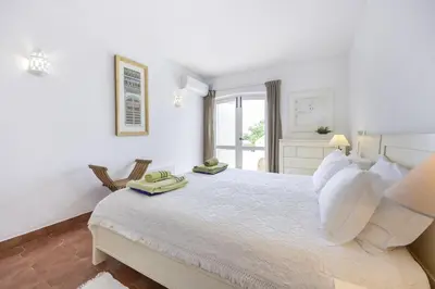 a white bedroom with a large bed and a window at CoolHousesAlgarve Luz, 3 bed linked house, pool, superb panoramic sea view, Casa das Buganvílias in Luz