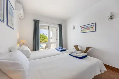 a white bedroom with two beds and a window at CoolHousesAlgarve Luz, 3 bed linked house, pool, superb panoramic sea view, Casa das Buganvílias in Luz