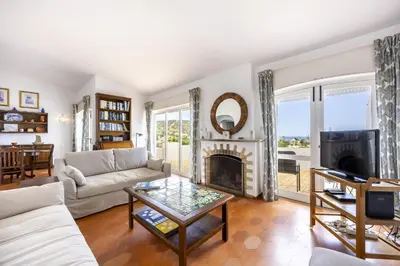 a living room with a couch and a fireplace at CoolHousesAlgarve Luz, 3 bed linked house, pool, superb panoramic sea view, Casa das Buganvílias in Luz