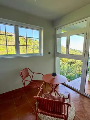 a room with two chairs and a table and windows at Green House in Calheta