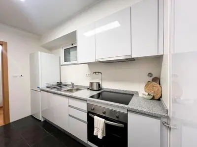 a white kitchen with white cabinets and a sink at Sandie's Serene Stay in Caniço