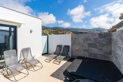 a balcony with three chairs and a table on a building at Star House -Jacuzzi & Aircon in Calheta