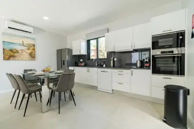 a kitchen with white cabinets and a table and chairs at Star House -Jacuzzi & Aircon in Calheta