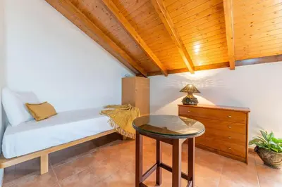a bedroom with a white bed with a wooden ceiling at Little Escape Madeira in Ponta Delgada