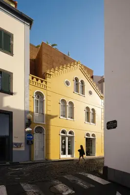 a person walking in front of a yellow building at Carmo 33 in Funchal