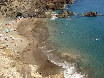 a group of people on a beach near the water at S A L - Beach Apartments Caniçal in Machico