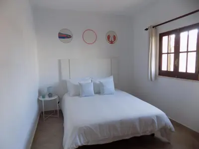 a white bedroom with a white bed and a window at Casa do Cercado, Sagres in Sagres