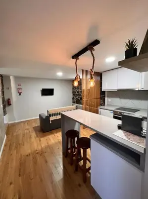 a kitchen and living room with a counter and stools at Roots Guesthouse - A in São Vicente