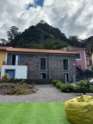 a stone house with a mountain in the background at Roots Guesthouse - A in São Vicente