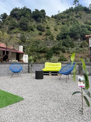 a patio with two blue chairs and a yellow couch at Roots Guesthouse- B in São Vicente