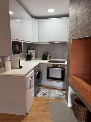 a kitchen with white appliances and a brick wall at Roots Guesthouse- B in São Vicente