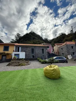 a yellow object sitting on the grass in front of a house at Roots Guesthouse- B in São Vicente